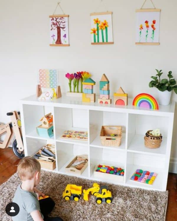 Montessori Playroom Inspiration - A white 8-cube cube storage unit sit against a white wall. On each shelf is a different wooden toy to play with. 