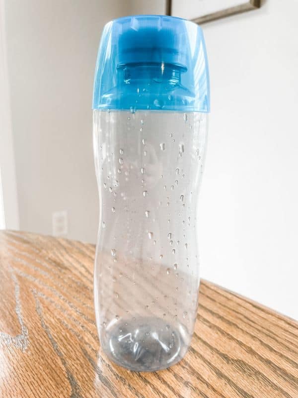 Image of an empty clear plastic water bottle with a blue cap. 