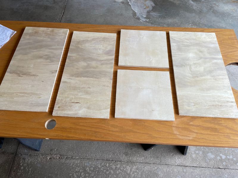 Image of the five plywood pieces of wood used to build the cabinet boxes. There are 3 long pieces and 2 short pieces. 