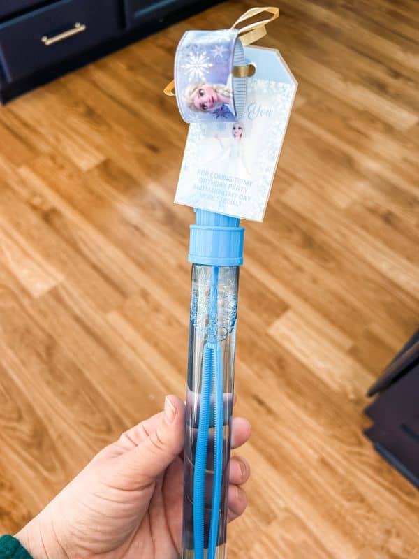 Frozen themed party favors for kids - a blue bubble wand with a frozen-themed slap bracelet and frozen thank you tag attached. 
