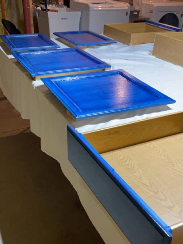 Image of cabinet fronts and drawers being painted blue for the navy and white two toned cabinets. 