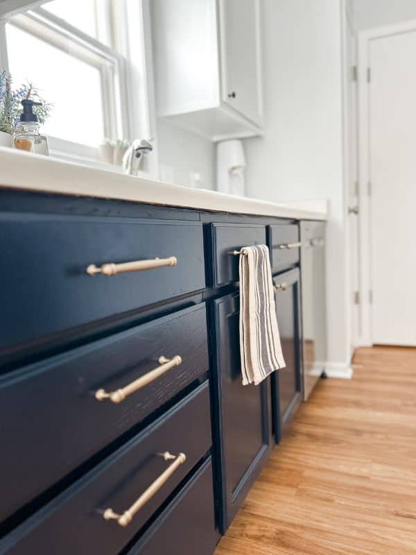 Image of the lower kitchen cabinets painted navy with gold hardware. 