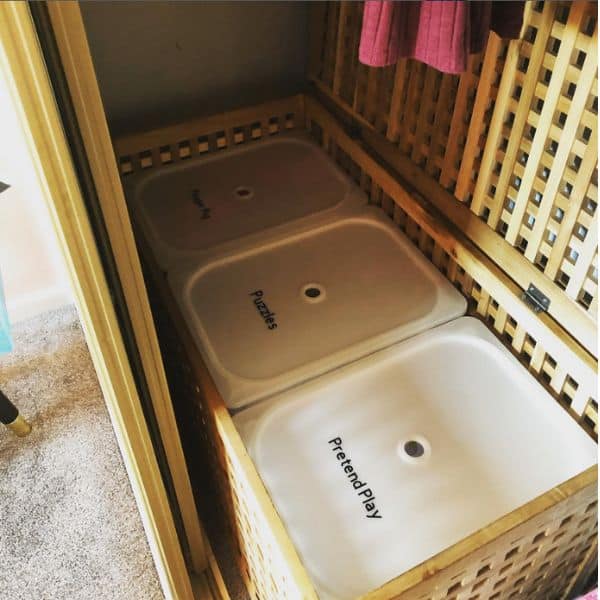 The tops of labeled IKEA Trofast bins placed inside a playroom closet. 