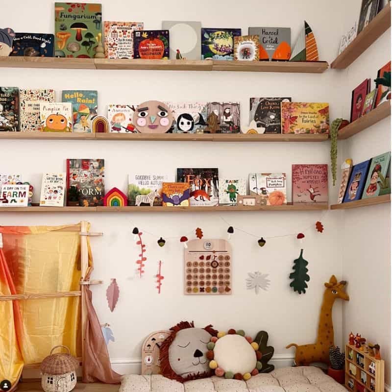 A reading corner in a child's room with books and toys on shelves wooden shelves. 