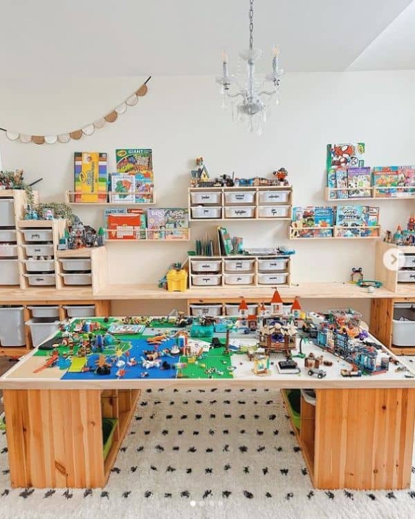 A playroom filled with lots of Legos and a large Lego table in the center of the room. 