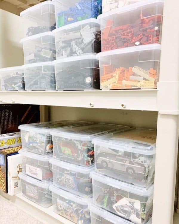 A shelf with multiple clear plastic bins filled with sorted Lego pieces by color and type