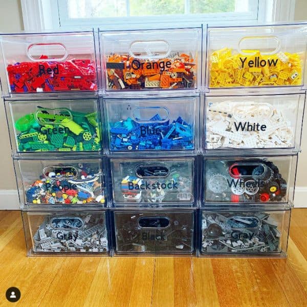 Clear plastic drawers labeled by color and type, filled with Lego pieces and neatly stacked.